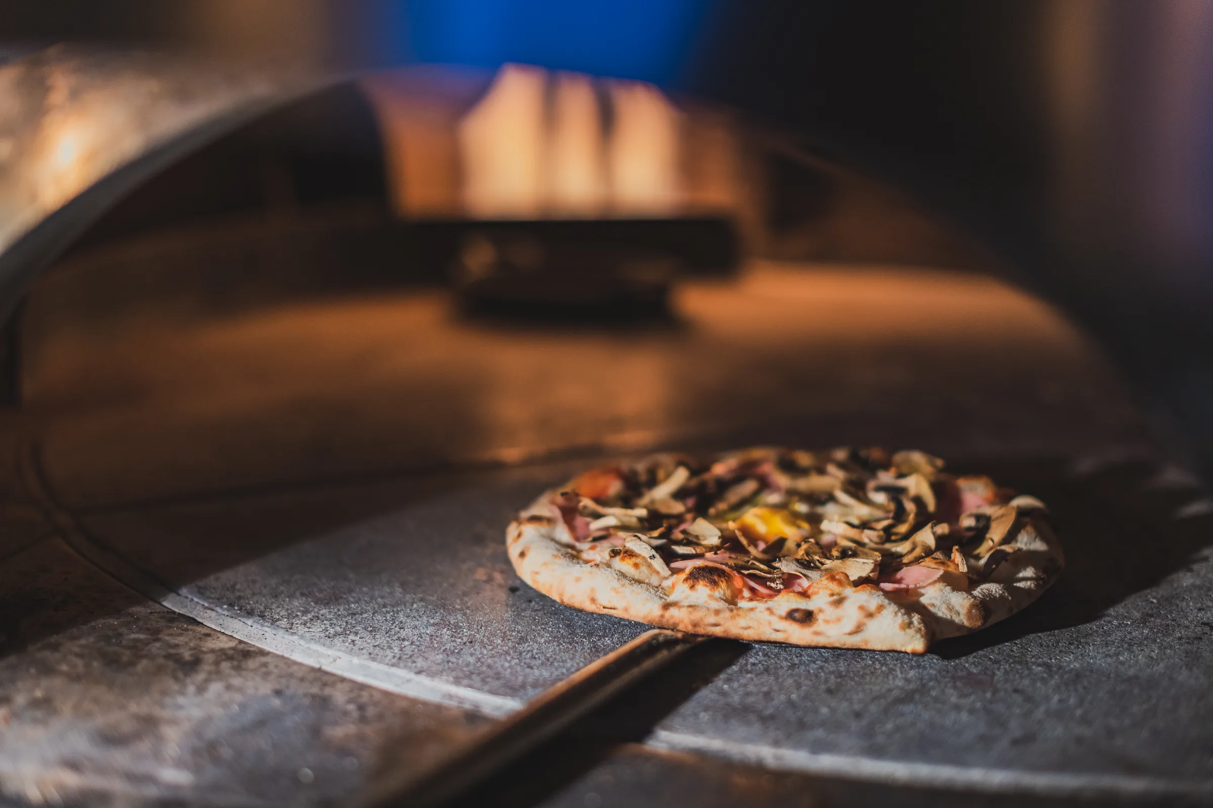 Pizza a entrar no forno a lenha da Forneria São Dinis